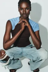 Camiseta de manga corta estilo raglán, con cuerpo principal marrón oscuro y mangas cortas en color celeste claro. Presenta cuello redondo con costuras a contraste.