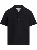 Camisa Calvin Klein de manga corta, confeccionada en algodón texturizado, con cuello tipo cubano, cierre frontal de botones y bolsillo de parche en el pecho con etiqueta de la marca.