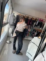 Top color crema con escote off-shoulder, mangas largas acampanadas y tejido de punto acanalado.