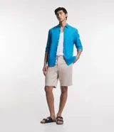 Bermuda de sarga color beige, de corte recto, con bolsillos laterales y traseros, cierre de botón y cremallera.