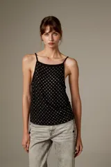 Top halter negro de viscosa, sin mangas, con tirantes finos y cobertura completa de ojalillos metálicos plateados.