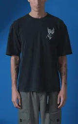 Remera de algodón premium con efecto nevado, corte oversize y cuello redondo. Presenta una estampa gráfica en color blanco en la espalda que incluye la palabra 'DESEO', una ilustración de una rosa y una figura alada, junto con frases poéticas.