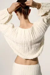 Top de punto texturizado en color beige, con escote redondo, mangas globo largas y acabado elástico fino en puños y bajo.
