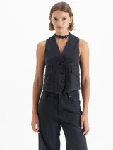 Chaleco de denim tipo sastrero color negro, de fit estándar, con escote en V, cierre frontal de botones y dos bolsillos de parche en el pecho.