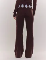 Conjunto de dos piezas compuesto por un cardigan de cuello alto con cierre frontal y un pantalón de silueta recta. Ambas prendas presentan un diseño de rombos en tonos marrón y celeste.