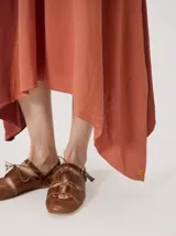 Vestido midi de lino con diseño geométrico en bloques de color negro, marrón y beige, cuello redondo, sin mangas y dobladillo asimétrico en punta.