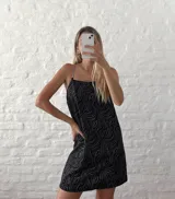 Vestido negro con estampado de ondas plateadas y tirantes de cadena metálica.