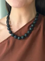 Collar corto de cuentas negras esféricas con diseño grabado, intercaladas con cuentas rectangulares lisas. El diseño presenta un estilo étnico y minimalista.