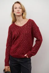 Buzo de punto color gris claro con motas oscuras, escote en V y mangas largas.