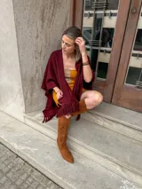 Ruana tejida color bordó con flecos en el borde inferior.