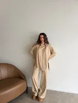 Conjunto oversize de dos piezas en tejido acanalado color beige, compuesto por una remera de manga larga con aberturas laterales y un pantalón largo de corte recto y holgado.