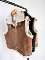 Chaleco estilo gamulán con interior y bordes de corderito sintético. Presenta cierre frontal, cuello solapa con hebillas decorativas y bolsillos laterales.