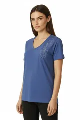 Remera de algodón color azul, con cuello en V, mangas cortas y detalle de diseño floral realizado con tachas plateadas en el hombro.