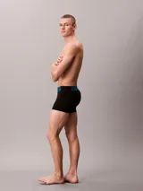 Pack de tres bóxers tipo trunk de Calvin Klein, color negro, con cinturilla elástica distintiva que presenta el logo de la marca en diferentes colores: verde menta, azul y blanco.