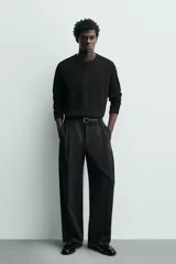 Mocasín de vestir negro con efecto acharolado, parte superior lisa con detalle de borlas, horma cuadrada y suela con ligero tacón.