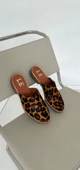 Mules de cuero con pelo estampado animal print de leopardo, con suela plana y plantilla de cuero.