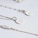 Conjunto de cadena fina y medalla circular de plata 925, con grabado lineal de figuras infantiles en el frente.
