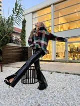 Pantalón de cuero de tiro alto con corte oxford, presenta un tajo en el ruedo lateral y un botón metálico distintivo.