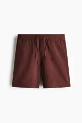 Short de corte relaxed fit confeccionado en suave tejido texturizado de mezcla de viscosa, en color bordó. Cuenta con cintura elástica con cordón ajustable, bolsillos laterales discretos y un bolsillo trasero ojal.