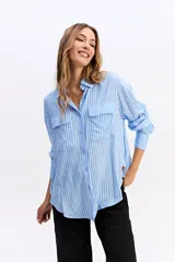 Camisa de manga larga con estampado de rayas verticales en tonos azul y blanco. Presenta cuello clásico, cierre frontal con botones y dos bolsillos tipo cargo en el pecho. Su diseño es de corte relajado y holgado.