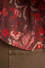 Blusa de viscosa color marrón con estampado floral en tonos rosados y rojos, de corte oversize, cuello en V con detalles de encaje y mangas largas abullonadas con inserciones de encaje.