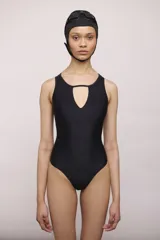 Malla de una pieza color negro, con escote redondo y abertura en forma de lágrima en el centro del busto. Presenta tirantes anchos y corte clásico en la pierna.