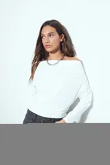 Top de manga larga con escote bote amplio, diseñado para usar ligeramente caído sobre los hombros. Presenta una silueta entallada y tejido liso, liviano y adaptable al cuerpo.