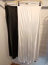 Falda midi de satén en color negro, con corte al bies y caída fluida que se ajusta suavemente a la silueta.