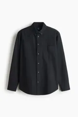 Camisa H&M de algodón Oxford, color negro, con cuello americano, bolsillo en el pecho, cierre frontal de botones y mangas largas.
