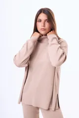 Buzo tejido de punto color negro, con cuello alto, manga larga y corte holgado con aberturas laterales en el ruedo.