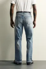 Jeans flare fit de denim de algodón en color celeste con lavado efecto desgastado. Presentan diseño de cinco bolsillos, tiro medio, cierre frontal con cremallera y botón, y bajo con acabado irregular.