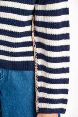 Sweater de lana con rayas horizontales en tonos rojo, rosa, beige y marrón. Presenta costuras decorativas en los laterales y puños en color violeta.