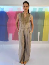 Mono largo color beige confeccionado en lino y algodón, con estampado texturizado en los laterales superiores. Presenta cuello mao, cierre invisible central, bolsillos laterales, cinto para ajustar en la cintura y tablón central delantero en las piernas.