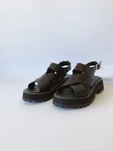 Sandalias negras de cuero con tiras cruzadas, plataforma track y hebilla lateral.