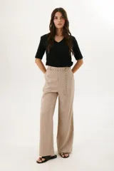 Pantalón de vestir color beige, de corte palazzo y tiro alto. Incluye cinturón de cadena plateada.