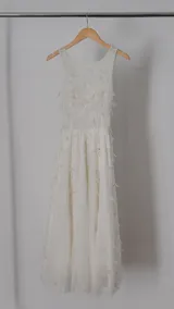 Vestido largo blanco de tul con escote redondo, detalles bordados y apliques en forma de flores.