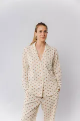 Pijama de algodón estampado con motas verdes y marrones, compuesto por una camisa de manga larga abotonada y un pantalón con elástico en la cintura y dos bolsillos.