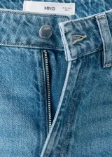 Pantalón de mezclilla de tiro medio con diseño acampanado estilo flare, trabillas para cinturón y clásico diseño de cinco bolsillos con cierre frontal de botón y cremallera.