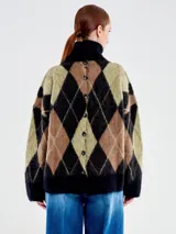 Buzo de punto con diseño de rombos en colores negro, marrón y verde, de calce amplio y cuello tortuga. Confeccionado en una mezcla de lana y alpaca con textura suave y vellosa.