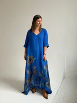 Vestido largo azul con cuello en V, mangas tres cuartos y gran estampado floral en la parte inferior.