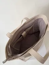 Cartera tipo shopper de cuero marrón texturado, con doble asa de hombro y un bolsillo frontal amplio con cierre de imán.