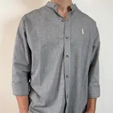 Camisa de algodón con cuello mao y estampado de rayas verticales finas. Presenta cierre frontal con botones y logo bordado en el pecho.