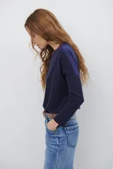 Remera de manga larga color bordó con cuello redondo en contraste color crema y costuras decorativas visibles en el ruedo y puños.