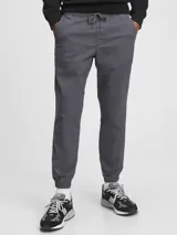 Pantalón tipo jogger de gabardina color gris oscuro, con cintura elástica con cordón ajustable y puños elásticos en los tobillos.