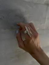 Anillo plateado con diseño abstracto y abierto, realizado en alpaca.