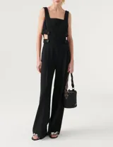 Mono negro con corte a la cintura y pantalón palazzo. Presenta breteles anchos y aberturas laterales con botones a presión.