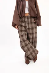 Pantalón tipo balloon de tejido plano con calce relajado, cintura elastizada y estampado cuadrillé en tonos marrones y beige.
