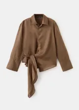 Blusa de ramio color marrón, de diseño recto, con cuello camisero, manga larga con puños abotonados, cierre frontal con botones y detalle de lazo cruzado.