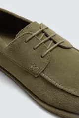 Zapato estilo náutico de hombre, color verde oliva, fabricado en piel con acabado serraje (gamuza). Presenta detalle de bordón en el empeine y horma redonda.