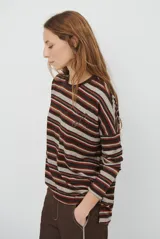Remera de manga larga con diseño de rayas horizontales en tonos marrones, beige y rojizos. Presenta cuello redondo y un detalle bordado en el pecho.